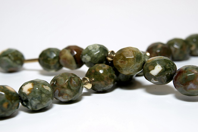 Mutmacherkette Rhyolith . Dieser Stein ist auch bekannt als Regenwaldjaspis. Er ist geschliffen und in grün bis braun Tönen gehalten. Perlenstärke 12 mm mit vergoldeten Stäbchen. Länge 48 cm. Karabinerverschluss 925 Silber 14 Karat vergoldet.