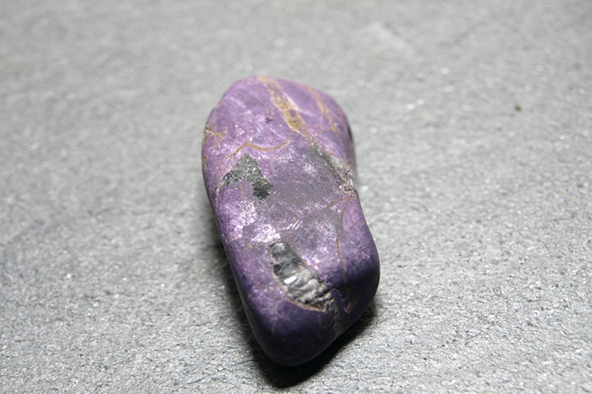Trommelstein Purpurit. Länglich, ca.3,5 x 1,2 cm, Farbe lila marmoriert